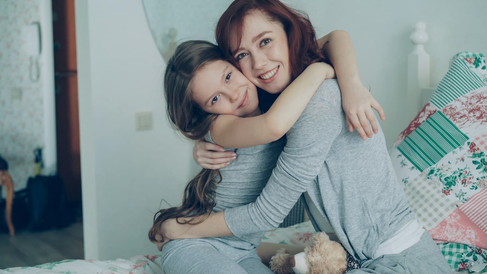 Una madre y su hija se abrazan sonriendo en casa.