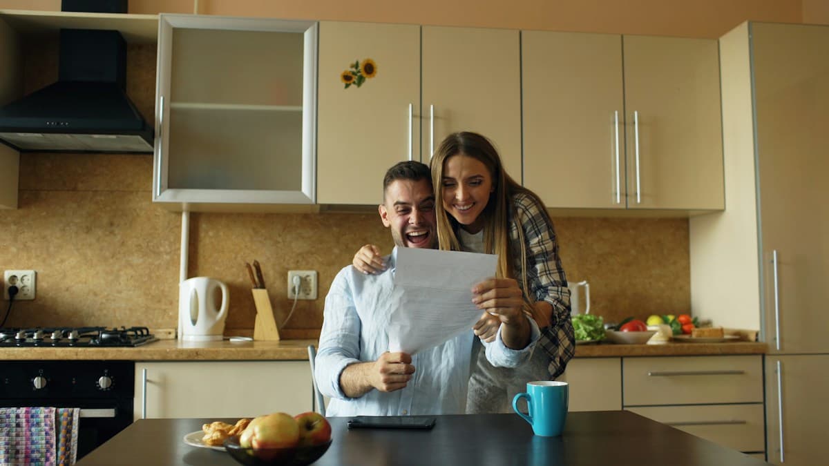 Una pareja joven revisa una carta en la cocina de su casa.